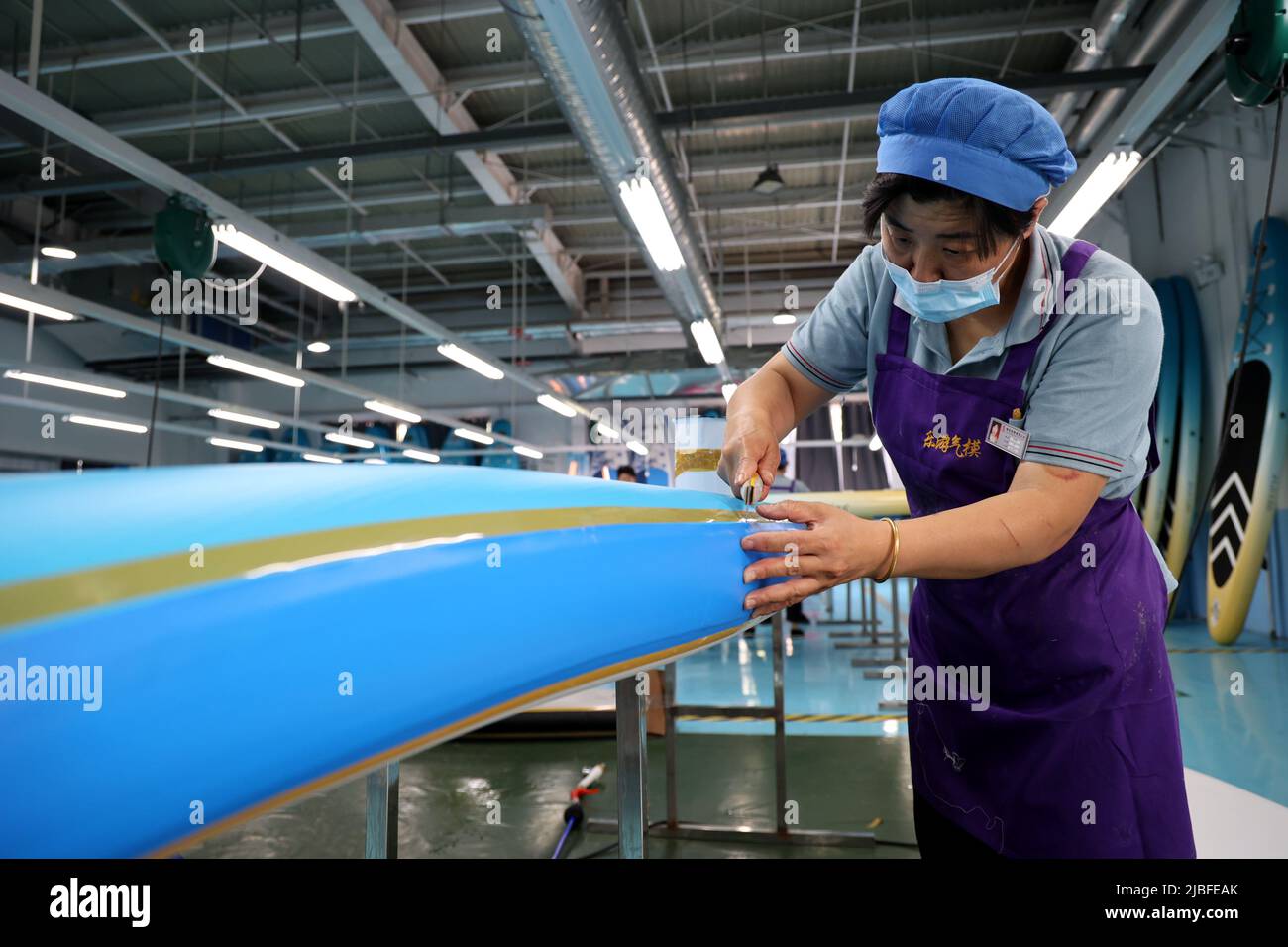 BINZHOU, CHINA - 6. JUNI 2022 - Ein Arbeiter produziert Surfbretter für Bestellungen aus dem Ausland in einer Surfbrett-Produktionswerkstatt in Binzhou, Shandong, Ostchina Stockfoto