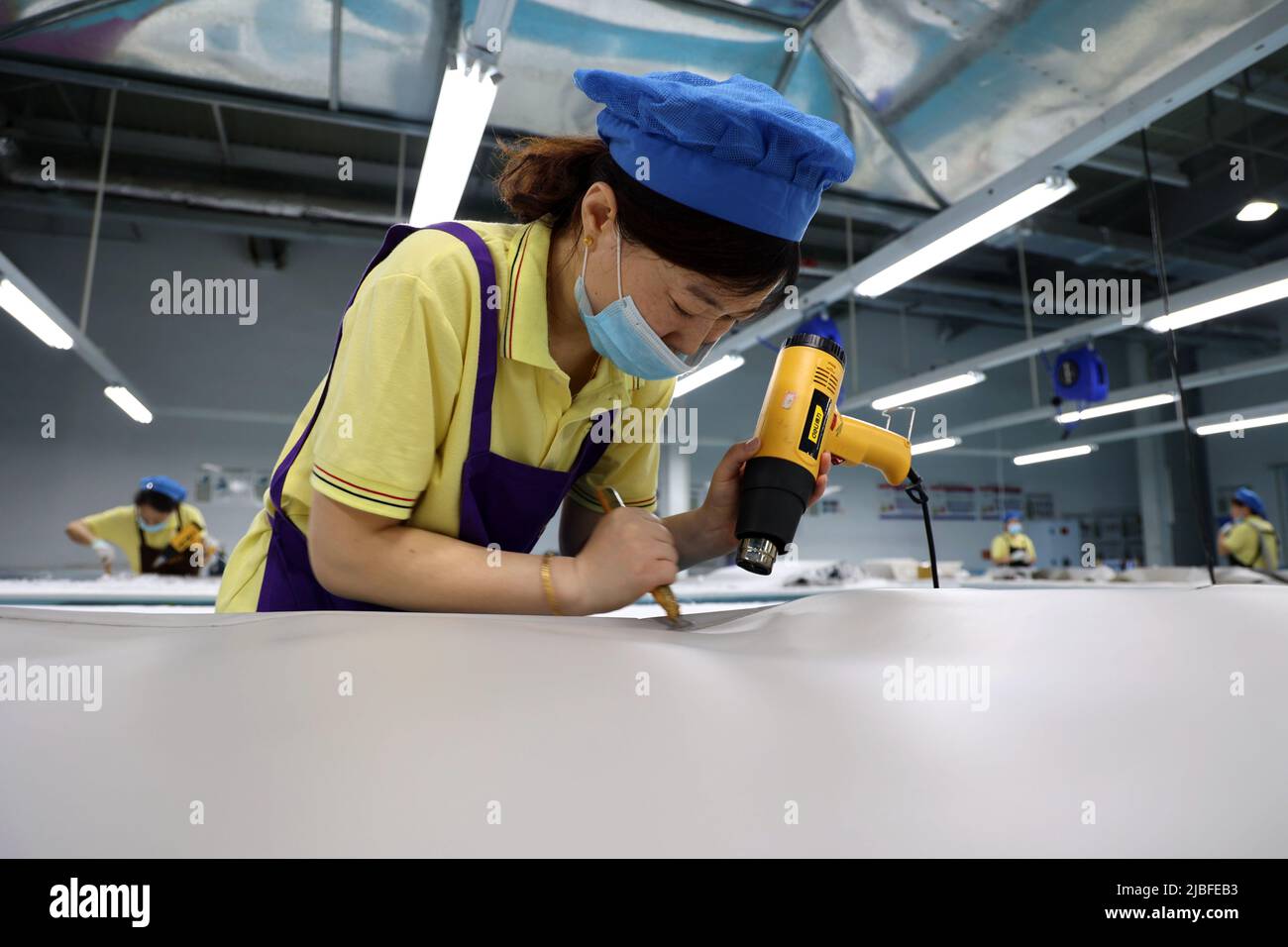 BINZHOU, CHINA - 6. JUNI 2022 - Ein Arbeiter produziert Surfbretter für Bestellungen aus dem Ausland in einer Surfbrett-Produktionswerkstatt in Binzhou, Shandong, Ostchina Stockfoto