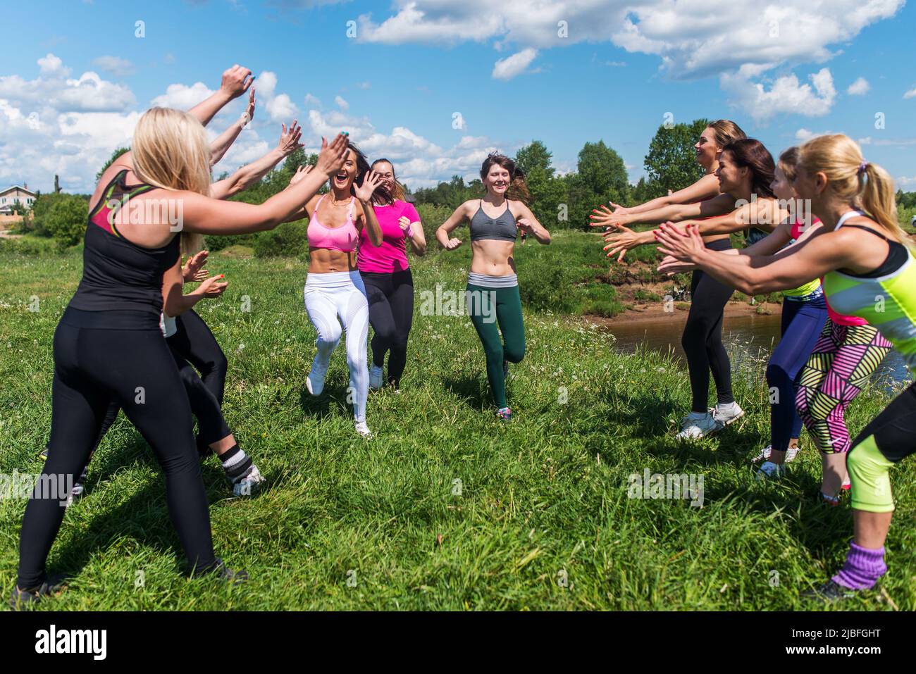 Eine Gruppe von aufgeregten Frauen, die die Finschline eines Marathons überquerten, der auf grasbewachsenem Land im Park lief Stockfoto