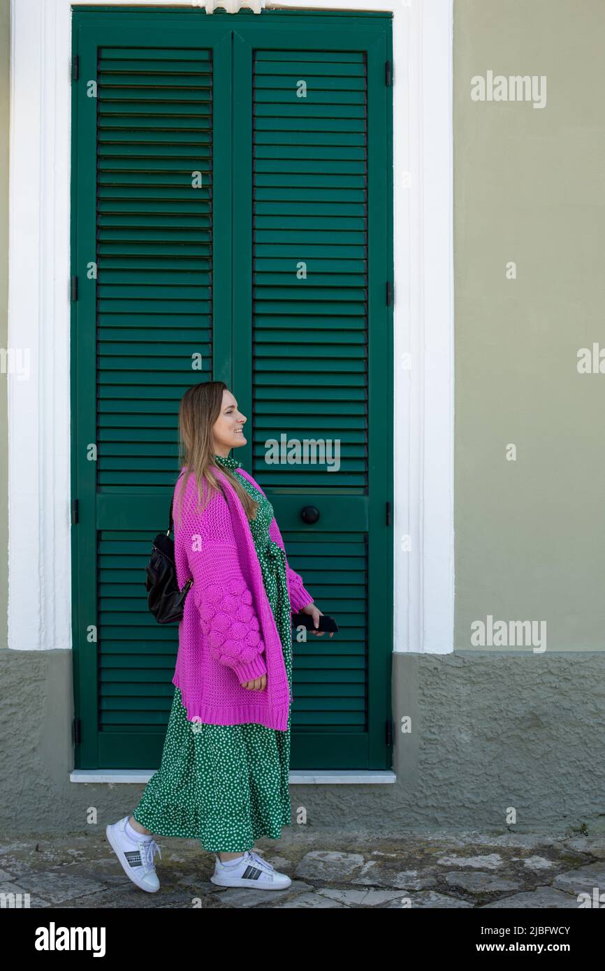Vertikales Bild der Frau, die in elegantem Kleid, Jacke, gegen große grüne Tür des louvre wegschaut. Besuchen Sie einen neuen Ort Stockfoto