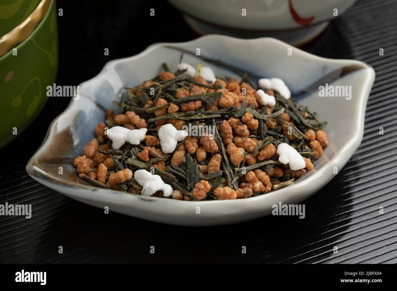 Schüssel mit Genmaicha, japanischem Tee, grünem Tee kombiniert mit geröstetem braunem Reis, von dem einige Körner aus nächster Nähe aufgetaucht sind Stockfoto