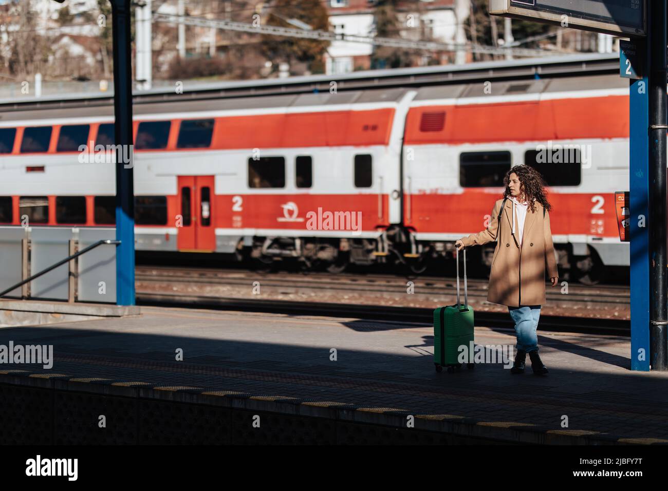 Junge Reisende Frau mit Gepäck wartet auf Zug am Bahnhof Bahnsteig.Zug im Hintergrund. Stockfoto