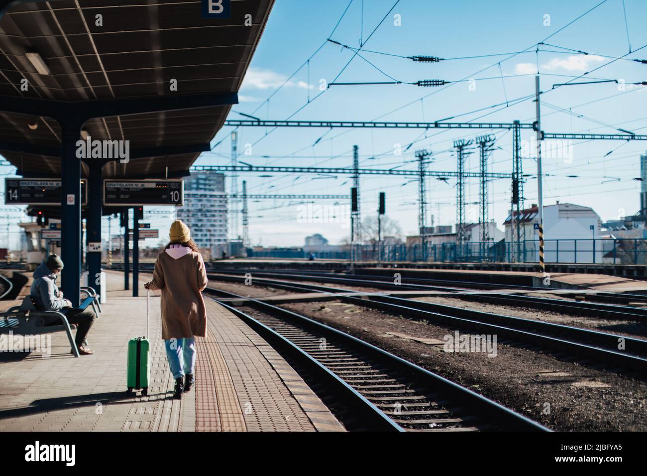 Glückliche junge Reisende Frau mit Gepäck, die am Bahnhofsplatz auf den Zug wartete Stockfoto