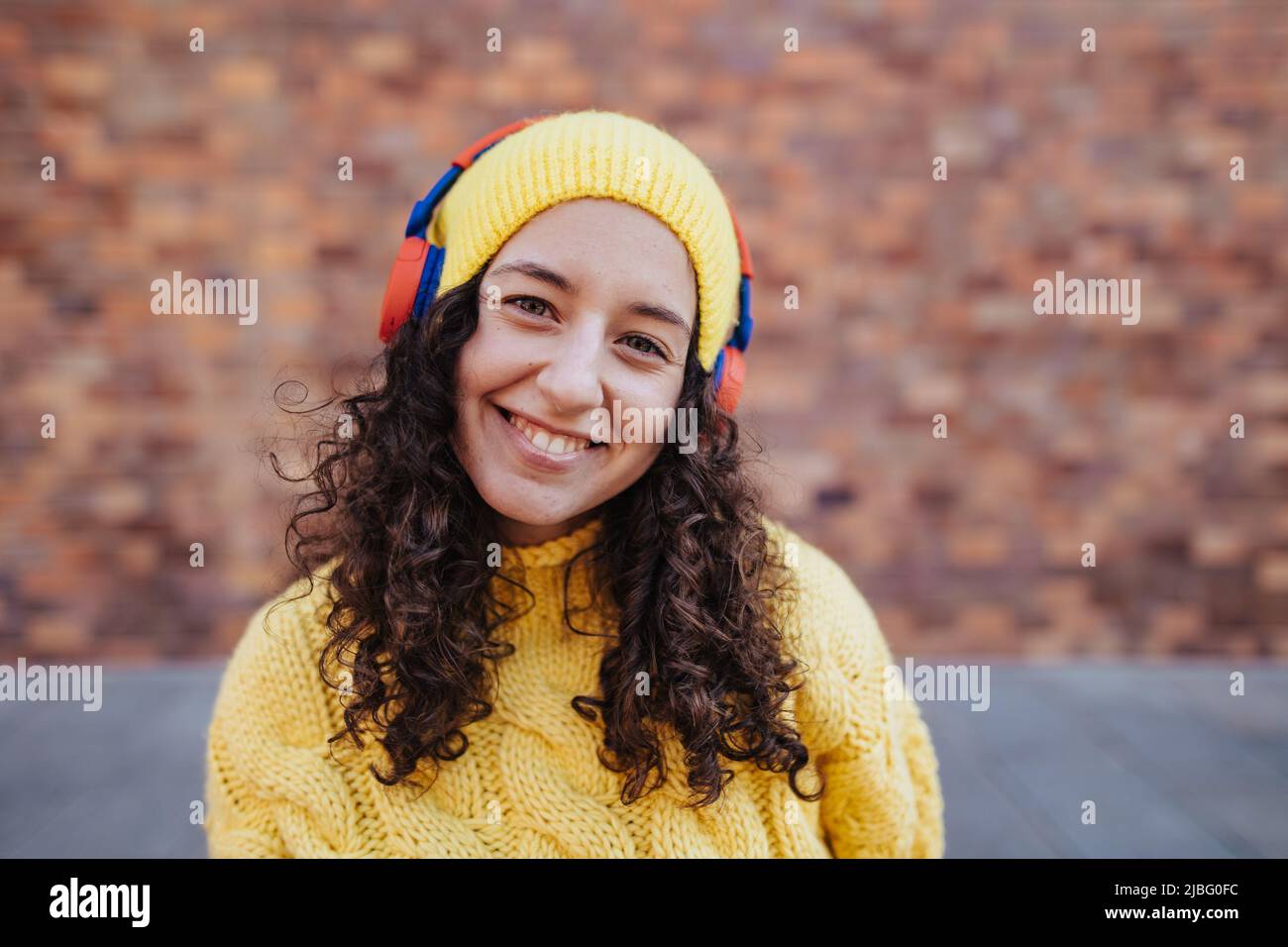Porträt einer glücklichen jungen Frau mit Kopfhörern in der Stadt Straße, Blick auf die Kamera. Stockfoto