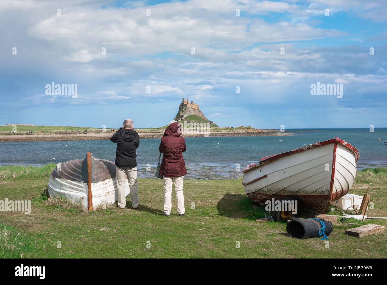 Urlaub in Großbritannien, Rückansicht eines reifen Paares im Urlaub auf Holy Island mit Blick über den Hafen nach Lindisfarne Castle, Northumberland, England, Großbritannien Stockfoto