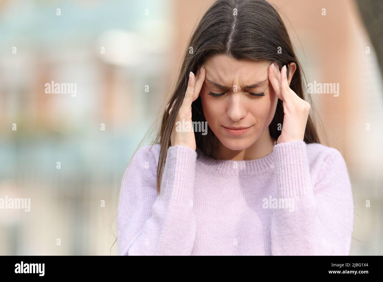 Vorderansicht Porträt eines Teenagers, der Kopfschmerzen auf der Straße leidet Stockfoto