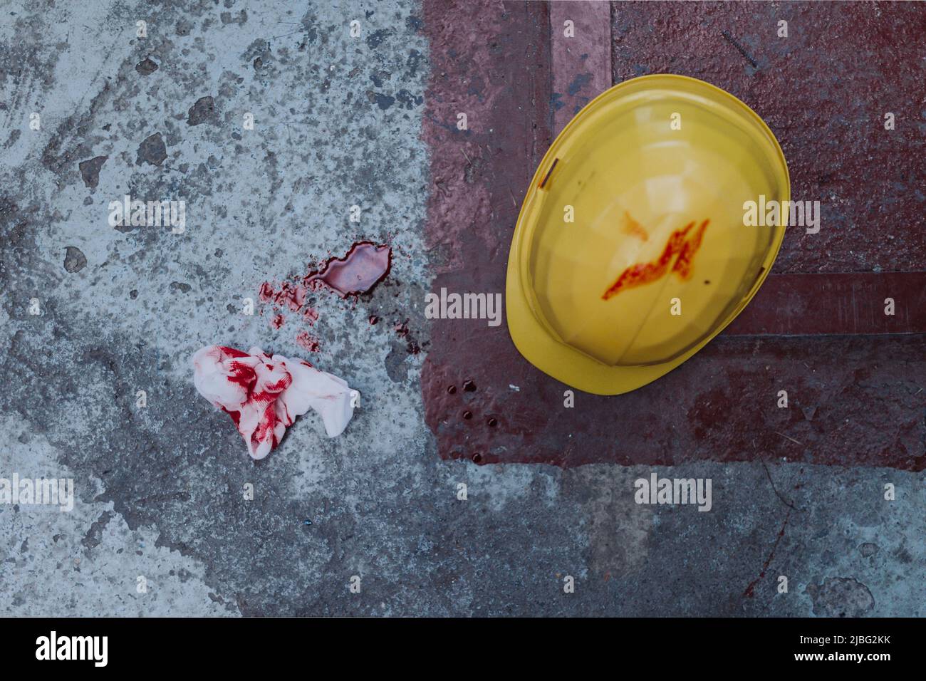 Helm und Gewebe mit Blutflecken und Blut auf dem Boden, Arbeitsunfallconcpet. Stockfoto