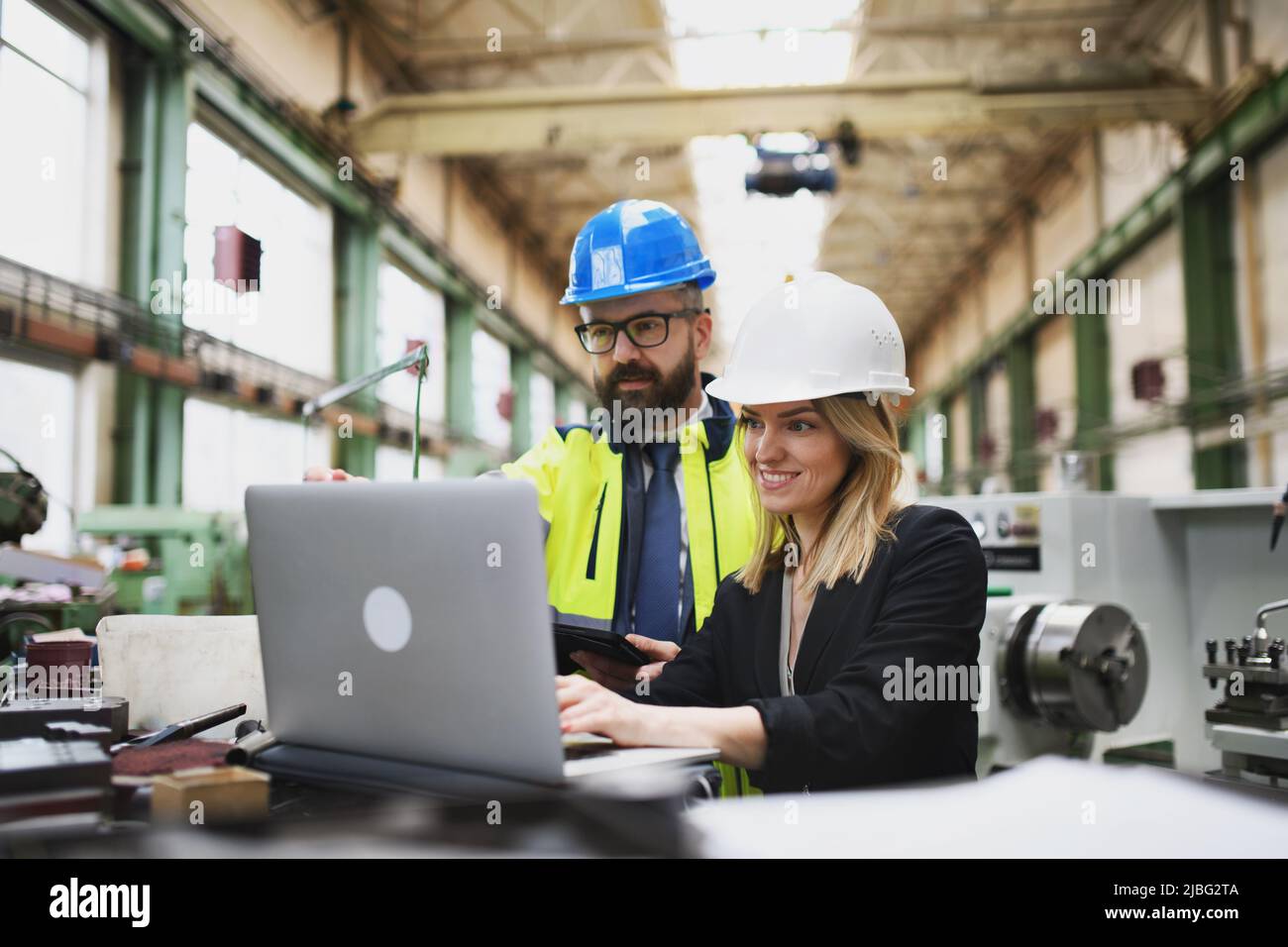 Ingenieure und Ingenieure diskutieren über das neue Maschinenprojekt der Fabrik und den Einsatz von Laptops. Stockfoto