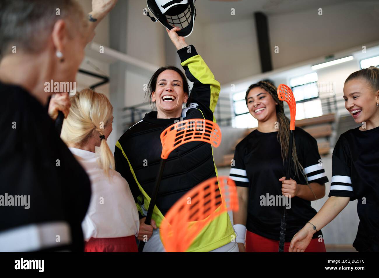 Gruppe von jungen und alten fröhlichen Frauen, Unihockey-Team-Spieler, in der Turnhalle abtretenden Sieg. Stockfoto