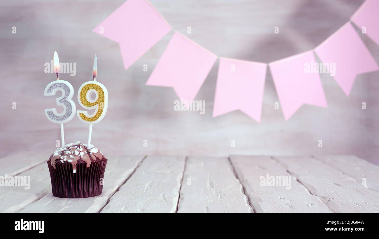 Geburtstagsnummer. Festlicher Hintergrund für ein Mädchen oder eine Frau mit einem Muffin und Kerzen brennend rosa in Pastellfarben mit Dekorationen für jeden Urlaub, Stockfoto