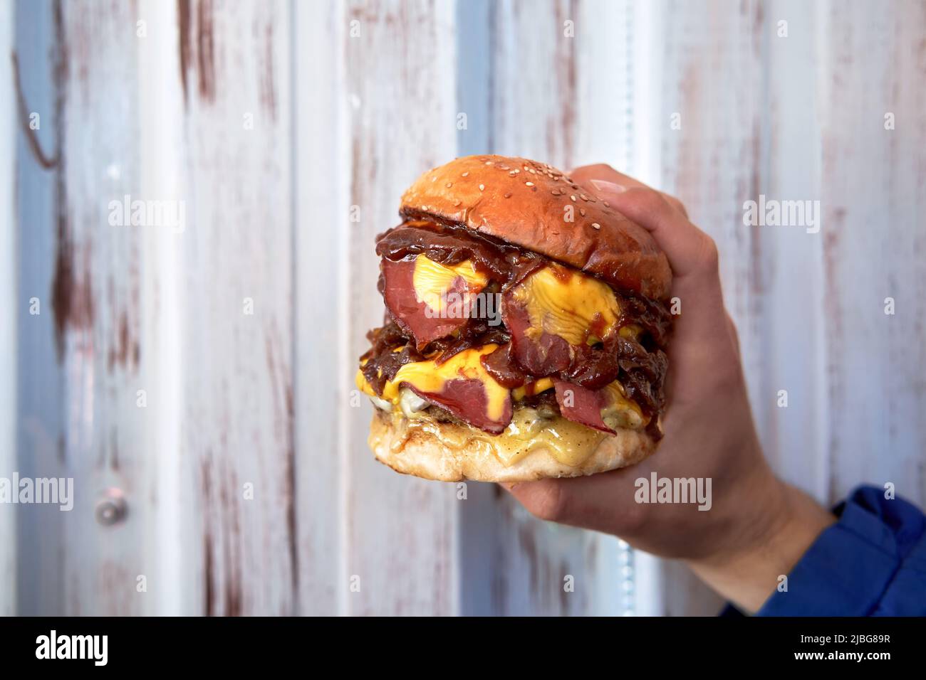 Männliche Hand hält einen leckeren Hamburger, Burger oder Cheeseburger. Stockfoto