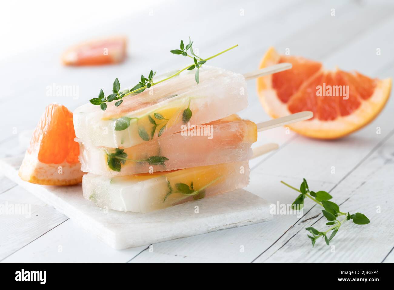 Ein kleiner Stapel Grapefruit-Thymian-Eiszapfen auf einem weißen Schiefertafel-Tisch. Stockfoto