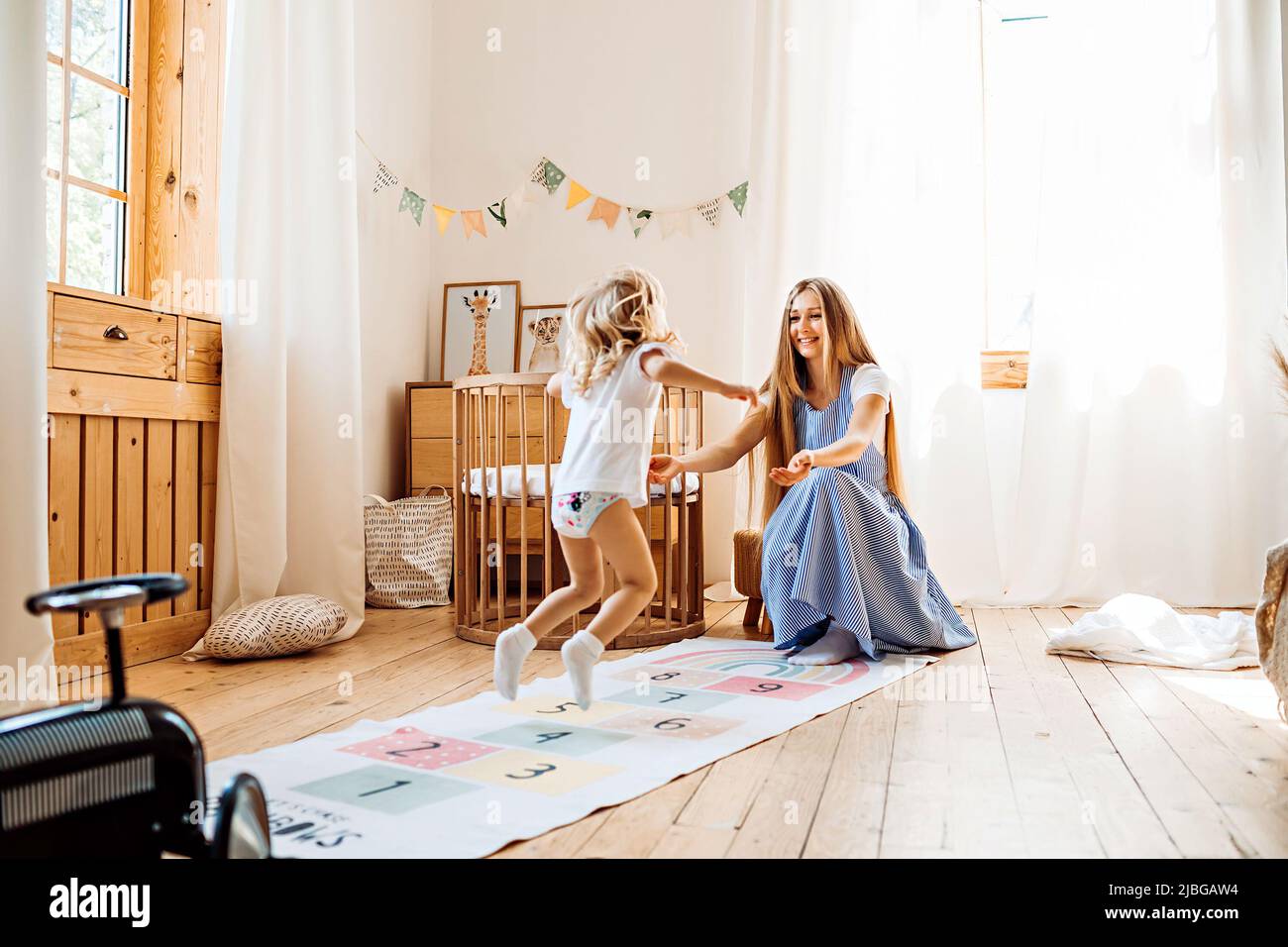Junge Mutter oder Babysitter spielen mit kleinen Mädchen zu Hause Stockfoto