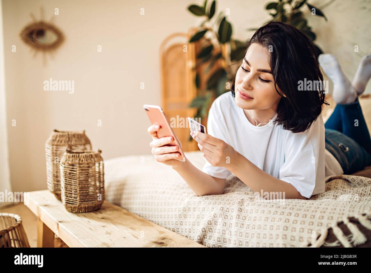 Lächelndes junges Mädchen kauft online per Telefon Stockfoto