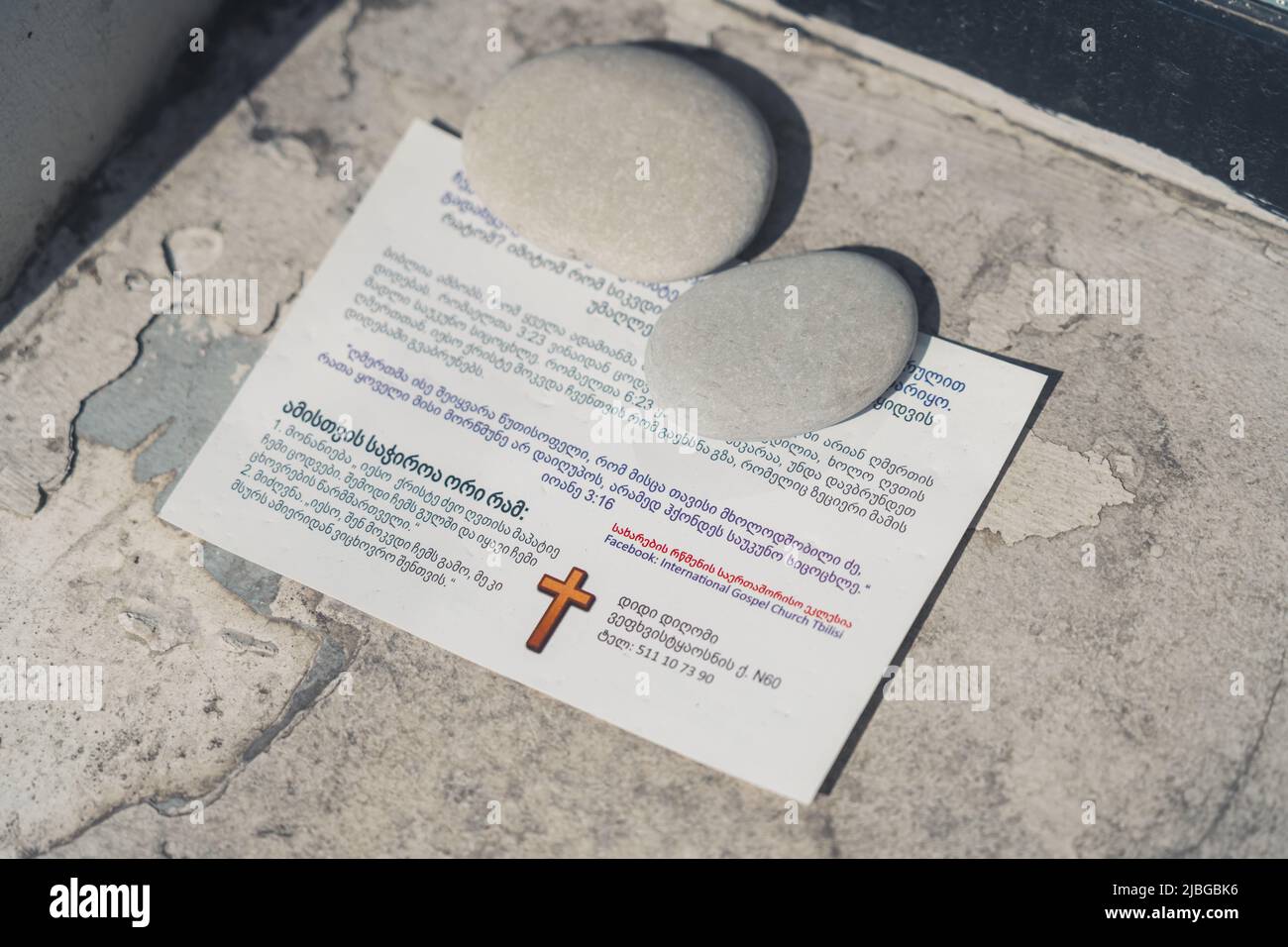 Kleines Papier mit georgischer Schrift über Religion und einem Kreuz darauf. Hochwertige Fotos Stockfoto
