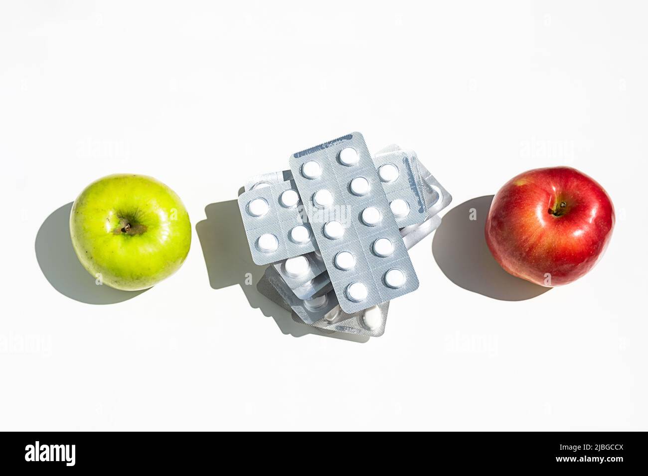 Äpfel und Pillen oder Vitaminkapseln auf weißem Tisch, Platz kopieren. Wellness, Ernährung oder Unterstützung für das Gesundheitskonzept. Stockfoto