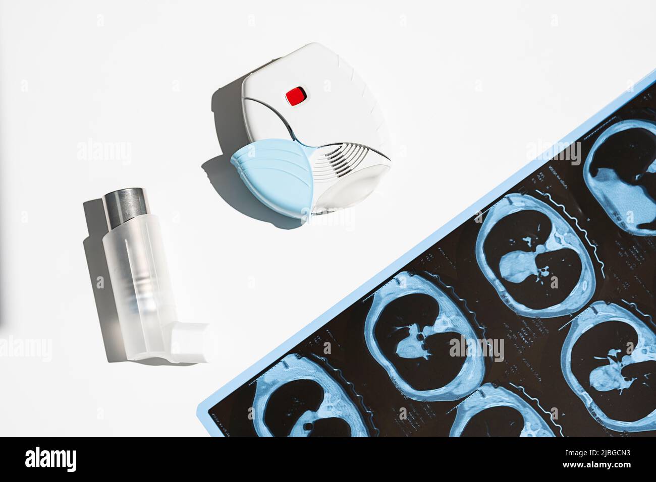 Einige Asthmainhalatoren und CT-Scans der Lunge auf weißem Tisch. Aerosol zur Inhalation zur Behandlung von Lungenentzündungen und zur Vorbeugung von Asthmaanfällen. Stockfoto