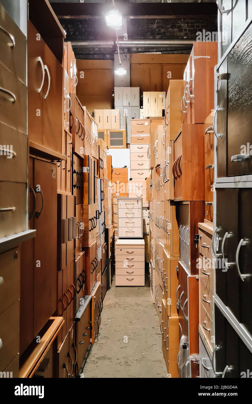 Lager von Büromöbeln. Ungewöhnlicher Korridor mit Nachttischen. Verkauf von gebrauchten Schränken. Möbelgeschäft. Stockfoto