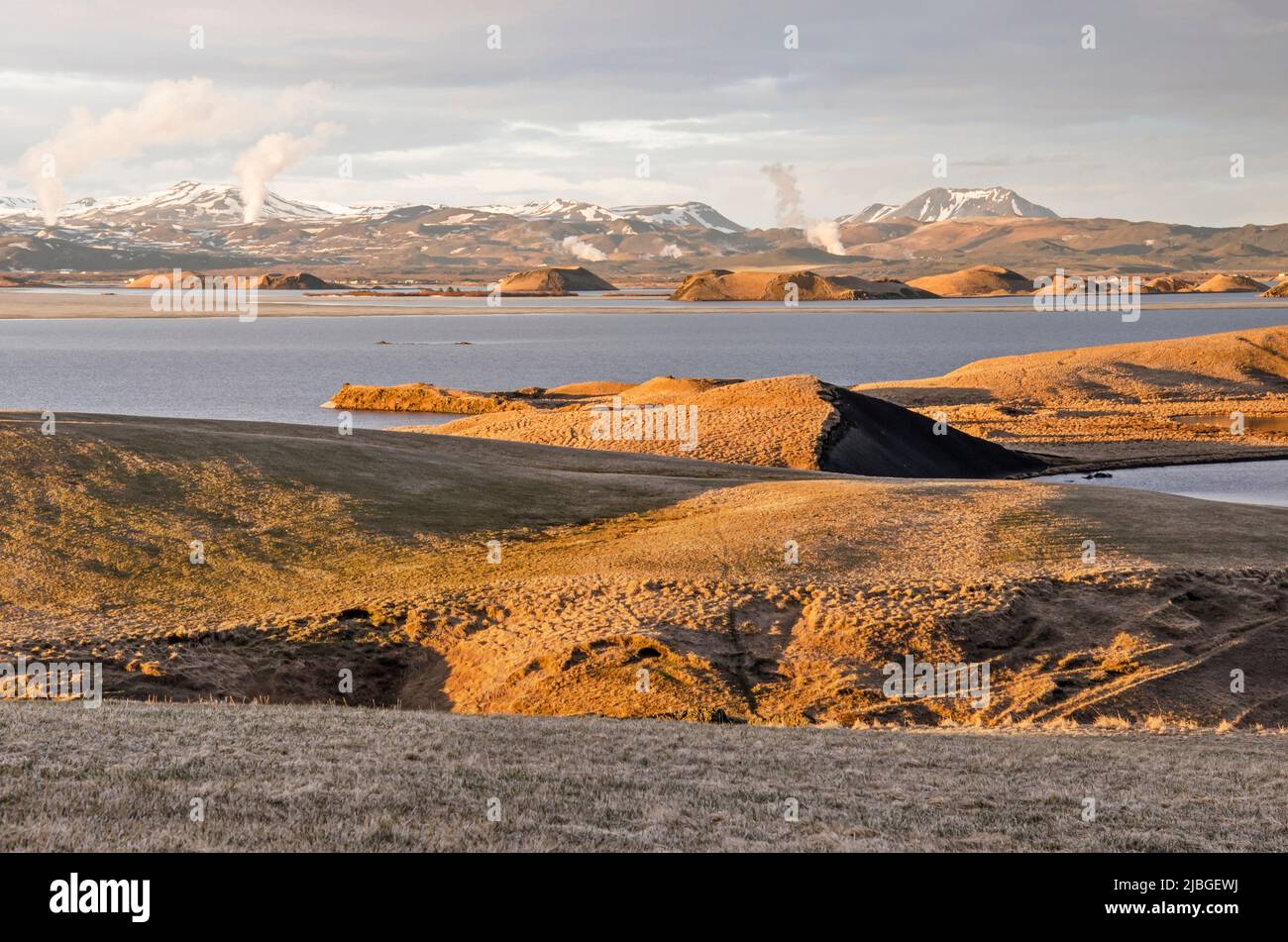 Skútustaðir, Island, 27. April 2022: Letzte Sonnenstrahlen erleuchten die seltsame Landschaft um den See Myvatn, aus der heiße Dampfwolken entweichen Stockfoto