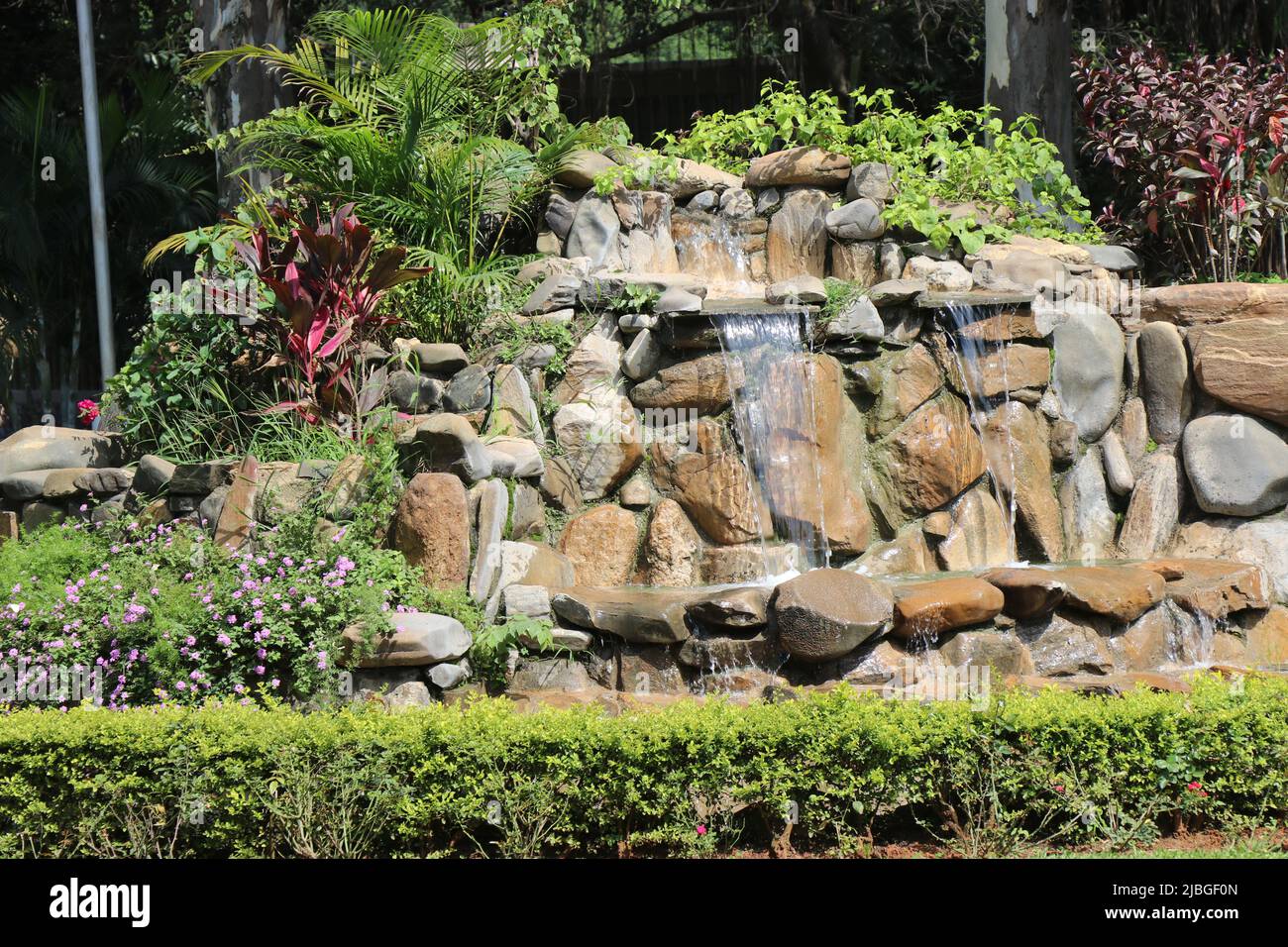Kleiner Garten mit Wasser über den Felsen an einem hellen Tag voller Grün Stockfoto
