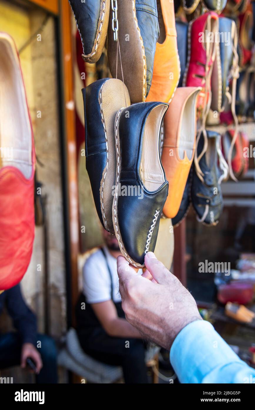 Ein Mann hält traditionelle jemenitische Schuhe in einem Marktstand im Freien in der Stadt Gaziantep des türkischen Landes. 05.20.2022 Stockfoto