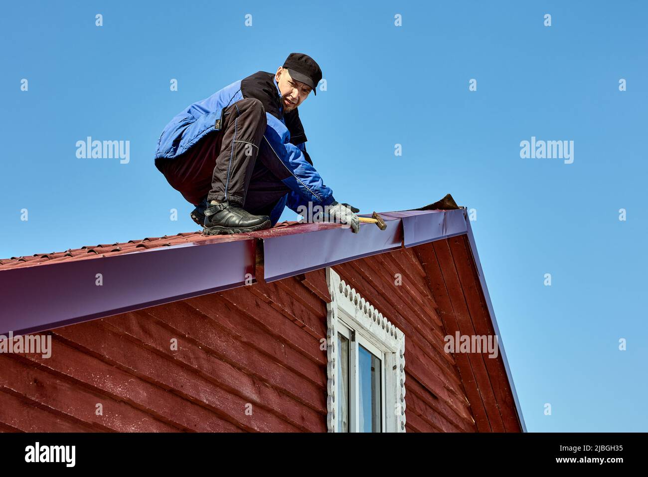 Dacharbeiten auf dem Land, Dachdecker fixiert Zinnbleche abgerissen durch Wind auf Dächern. Stockfoto