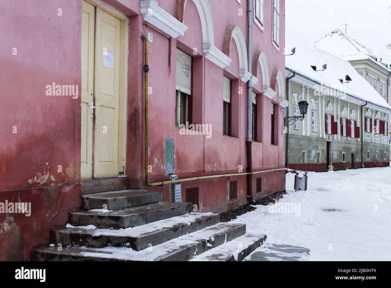 Das Bild von Eingang und Stufen mit gelber Tür des alten Hauses in der Innenstadt von Brasov, Rumänien im Winter. Stockfoto