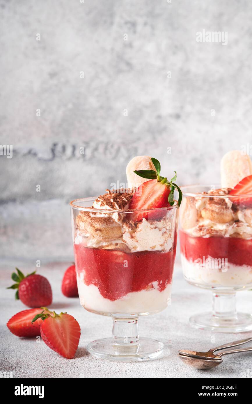 Erdbeere Tiramisu. Traditionelles italienisches Dessert Tiramisu im Glas mit frischen Erdbeer- und Minzblättern auf altem grauen Beton-Hintergrund-Tisch Backgro Stockfoto