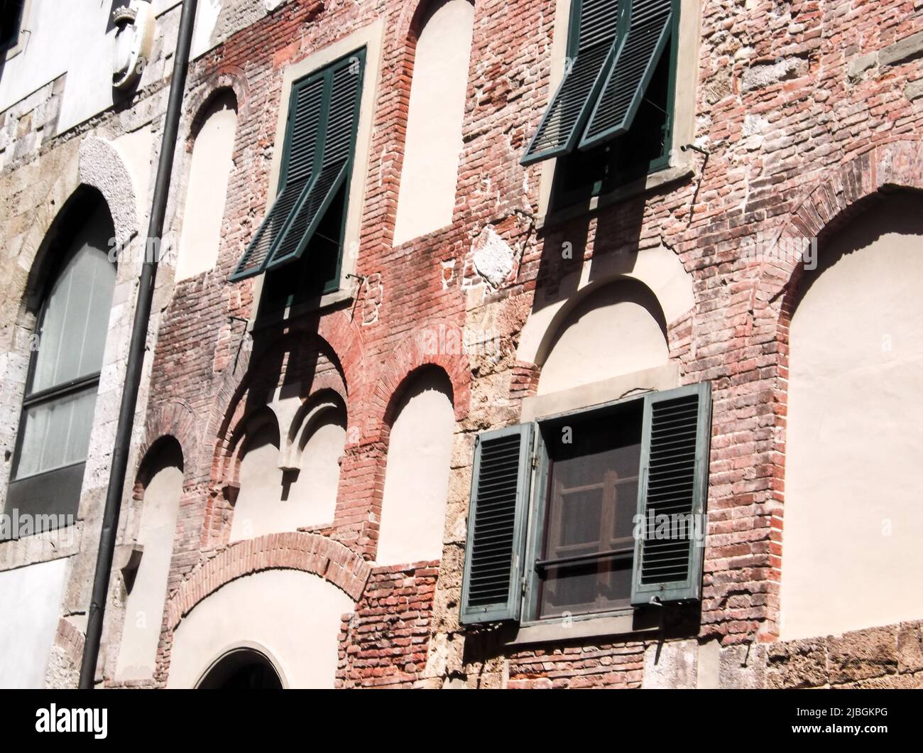 Das Nahaufnahme Bild von Holzfenster auf alten Backsteinwohnung in sonnigen Tag, Italien. Die Wohnung außen ist verblasst und veraltet. Stockfoto