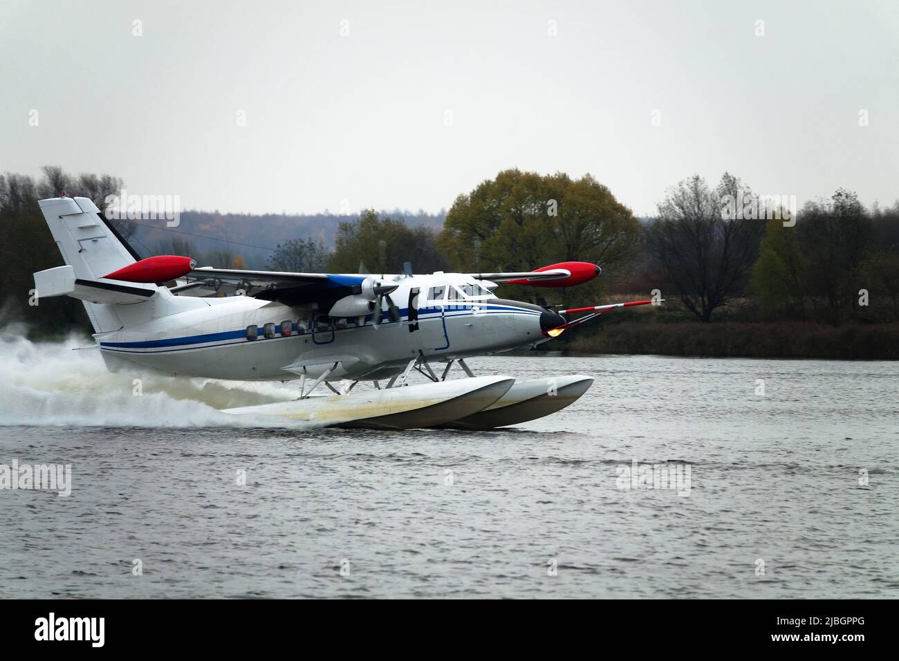 Das zweimotorige Wasserflugzeug ein Wasserflugzeug steigt aus dem Wasser, aus dem Waldsee, dem nördlichen Land auf. Wasserflugzeug Stockfoto