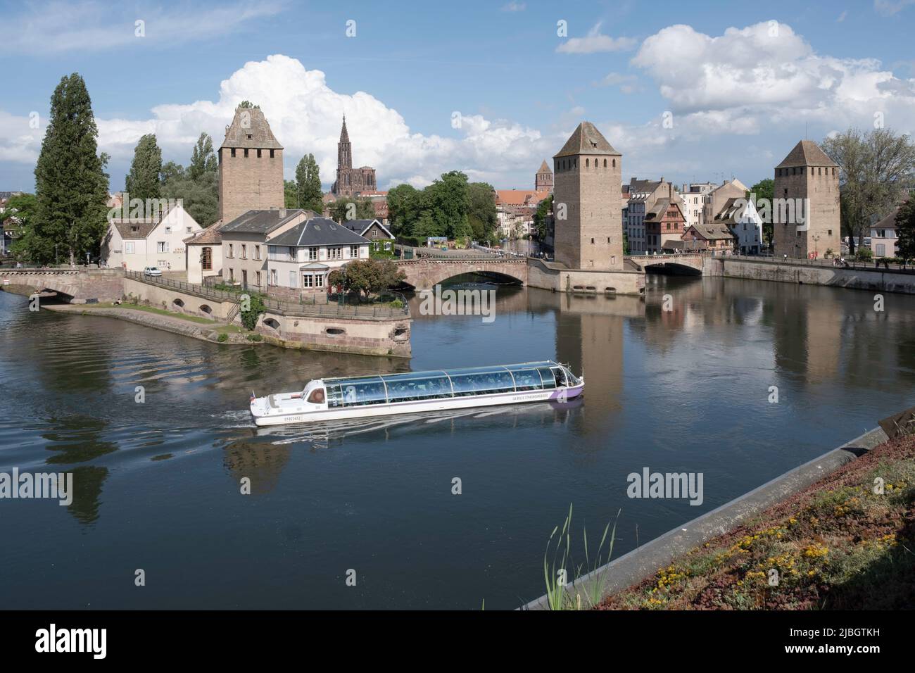Blick auf die historische Altstadt Petite France am Ill, Türme, überdachte Brücken und Kanäle mit Touristenboot in Strassburg aus der Staustufe Stockfoto