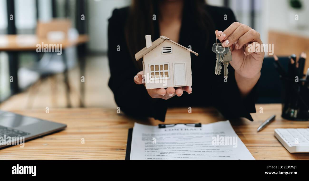 Immobilienmakler, der Schlüsselhaus und Modell übergibt, das Versicherungskonzept vermietet und verkauft. Stockfoto