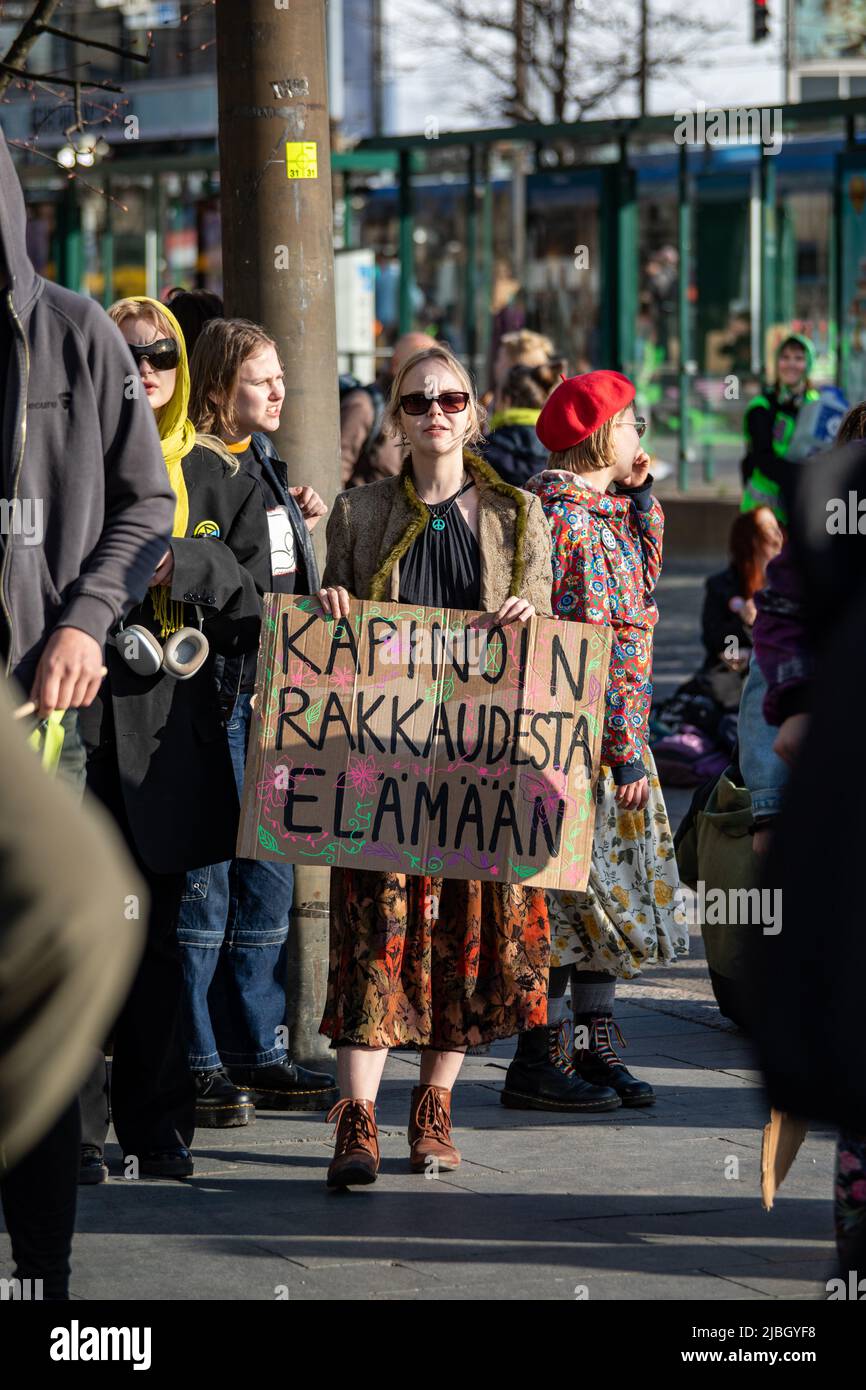 Kapinoin rakkaudesta elämään. Junge Frau mit einem handgeschriebenen Pappschild bei der Ylikulutuskapina-Demonstration von Elokapina in Helsinki, Finnland. Stockfoto