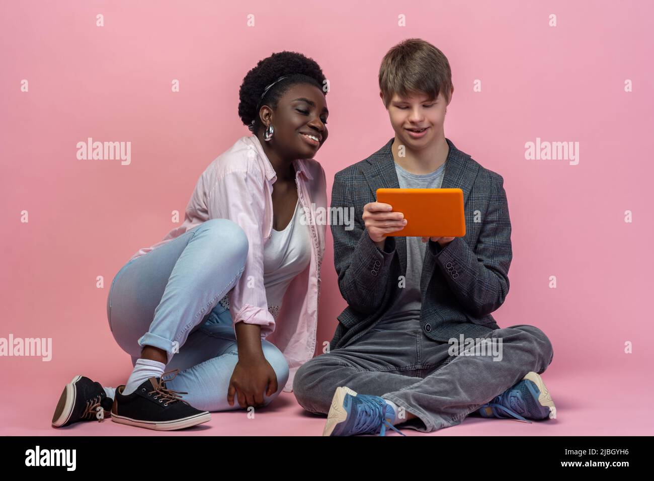 Typ mit Tablet und Frau auf dem Boden Stockfoto