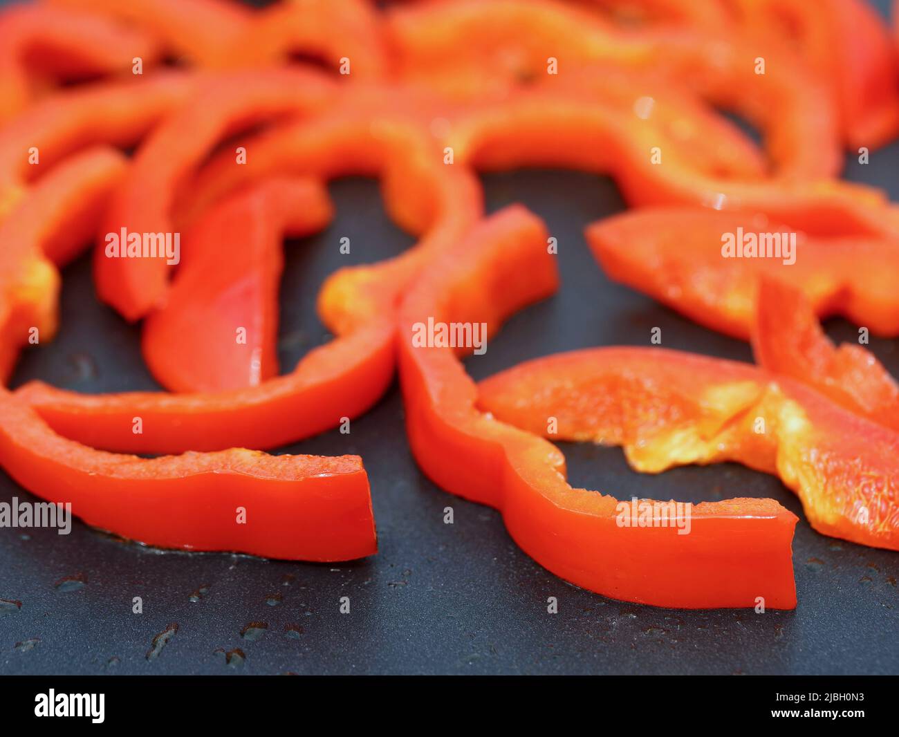 Nahaufnahme von geschnittenen roten Paprika auf einer antihaftbeschichten Grillplatte, gesundem Gemüse zum Grillen oder Braten Stockfoto