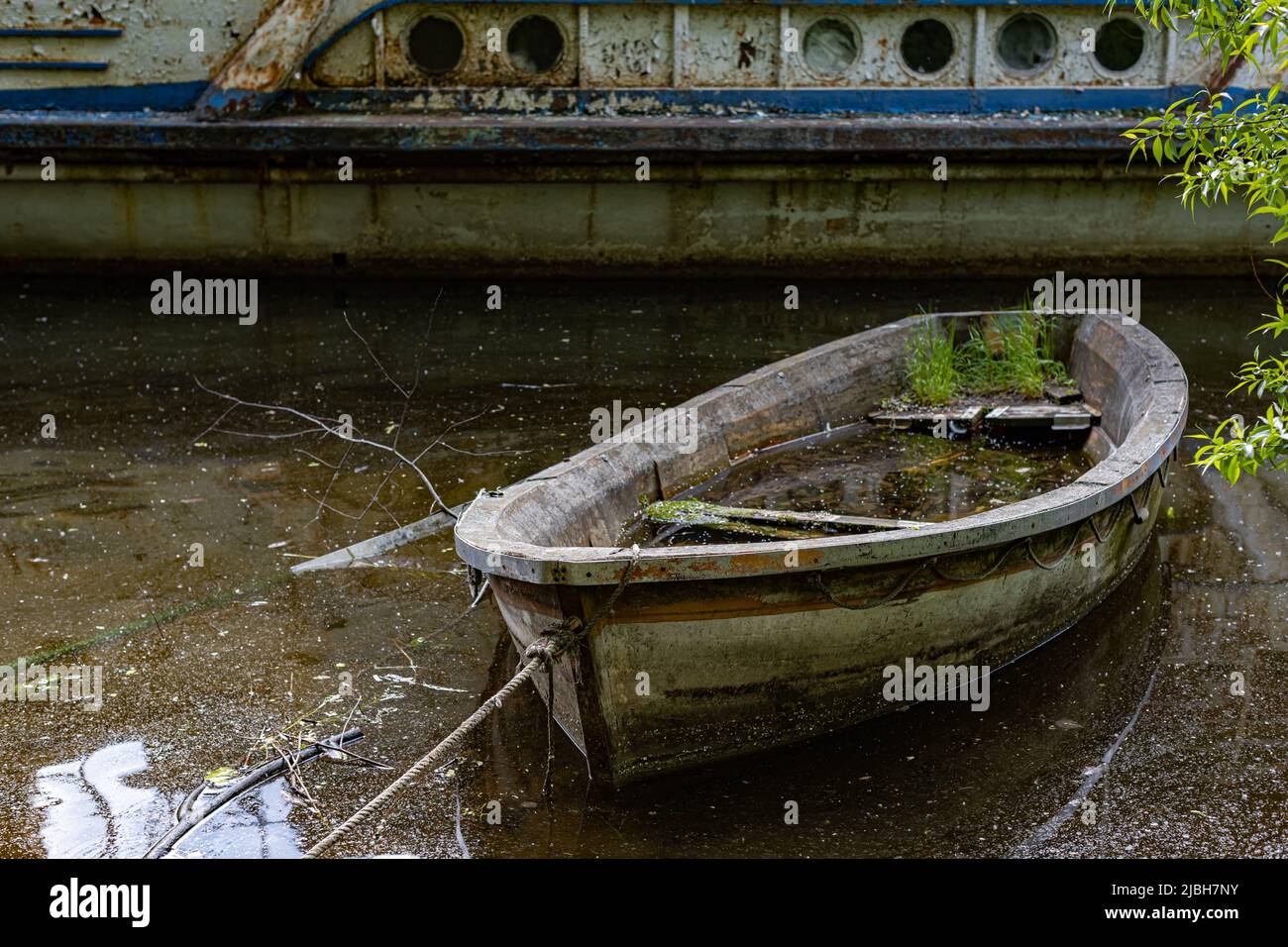 Altes verfaultes versunkenes Boot an das Ufer gebunden Stockfoto