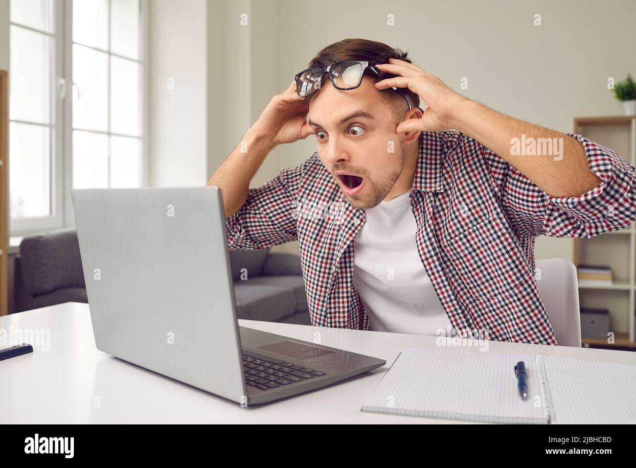 Aufgeregt betäubt Mann mit schockierten Ausdruck liest E-Mail auf Laptop-Bildschirm mit günstigen Vorschlag. Stockfoto