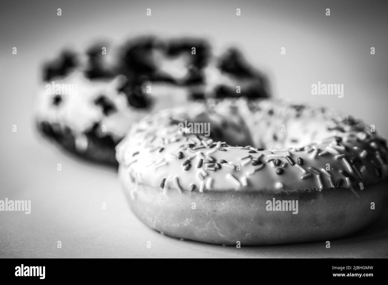 Nahaufnahme eines Ringdonuts mit weißer Glasur und hunderttausenden Schwarz-Weiß-Bildern Stockfoto