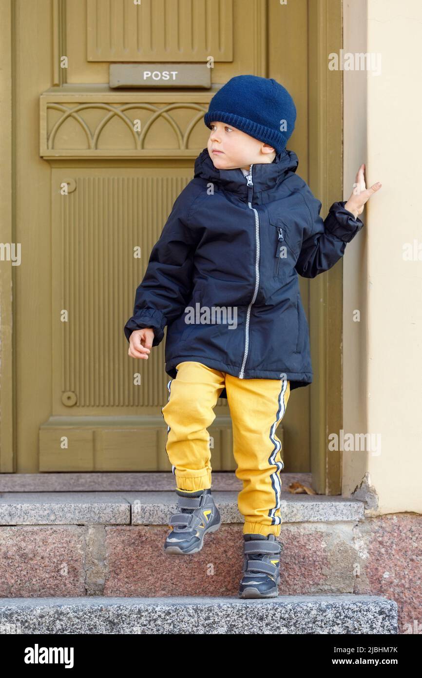 Netter Junge an einem Herbsttag vor der Tür der alten Post. Stockfoto