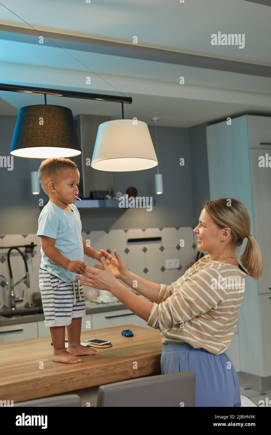 Porträt von glücklichen kaukasischen Mutter spielt mit niedlichen Kleinkind Junge in der Küche zu Hause Innenraum Stockfoto