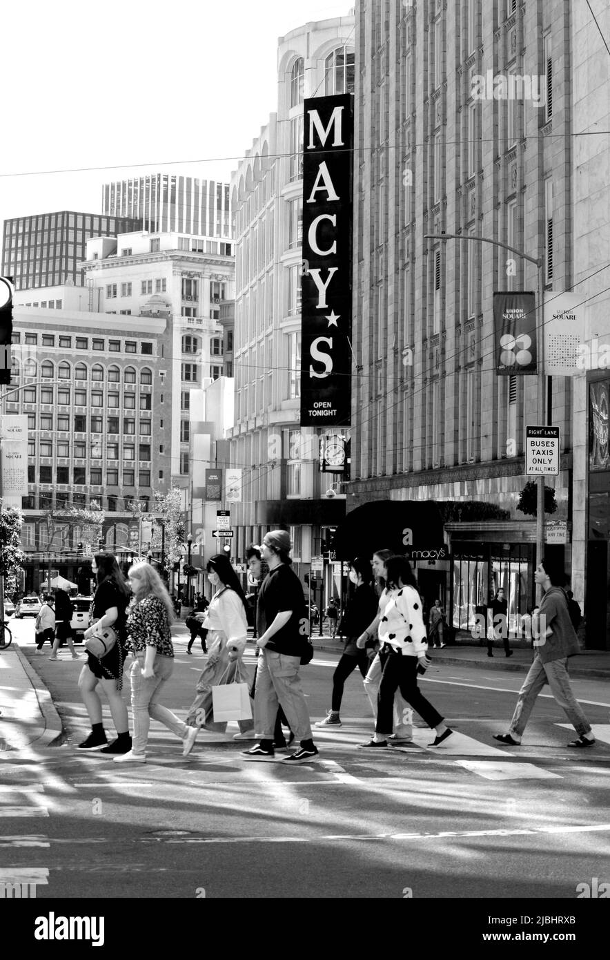 Fußgänger überqueren eine Straße an einer belebten Kreuzung vor dem Kaufhaus Macy's in San Francisco, Kalifornien. Stockfoto