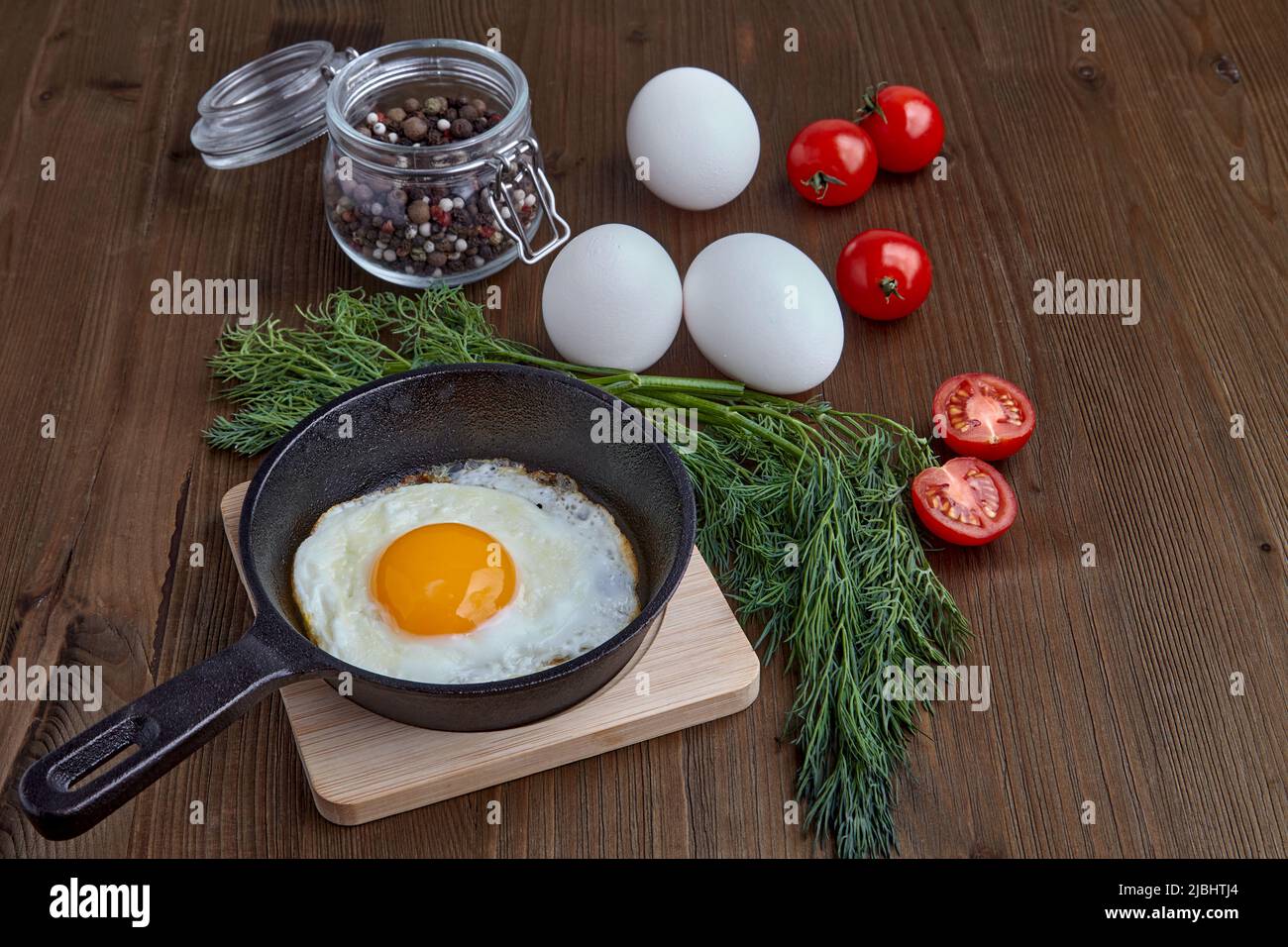 Gebratenes Hühnerei in einer kleinen Pfanne mit einem Ständer, einem ...