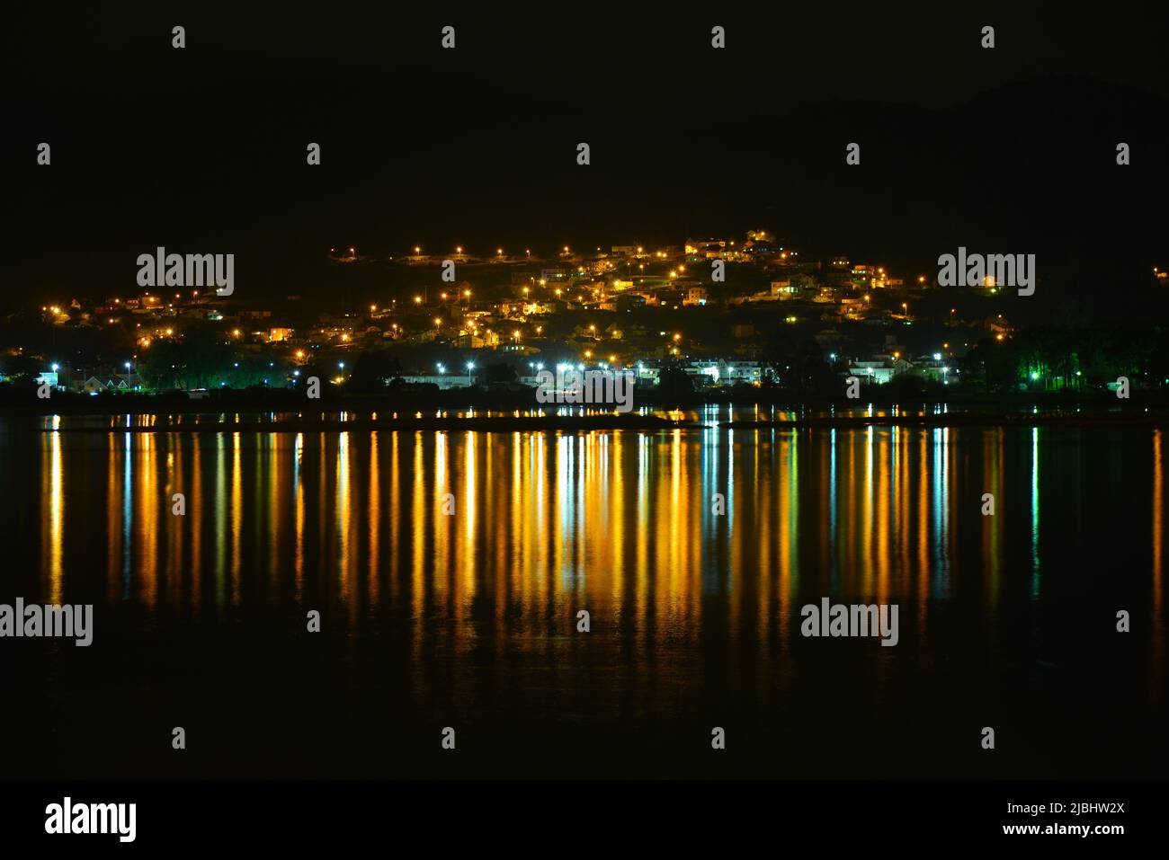 In einer dunklen Nacht reflektierten sich Lichter im Wasser Stockfoto