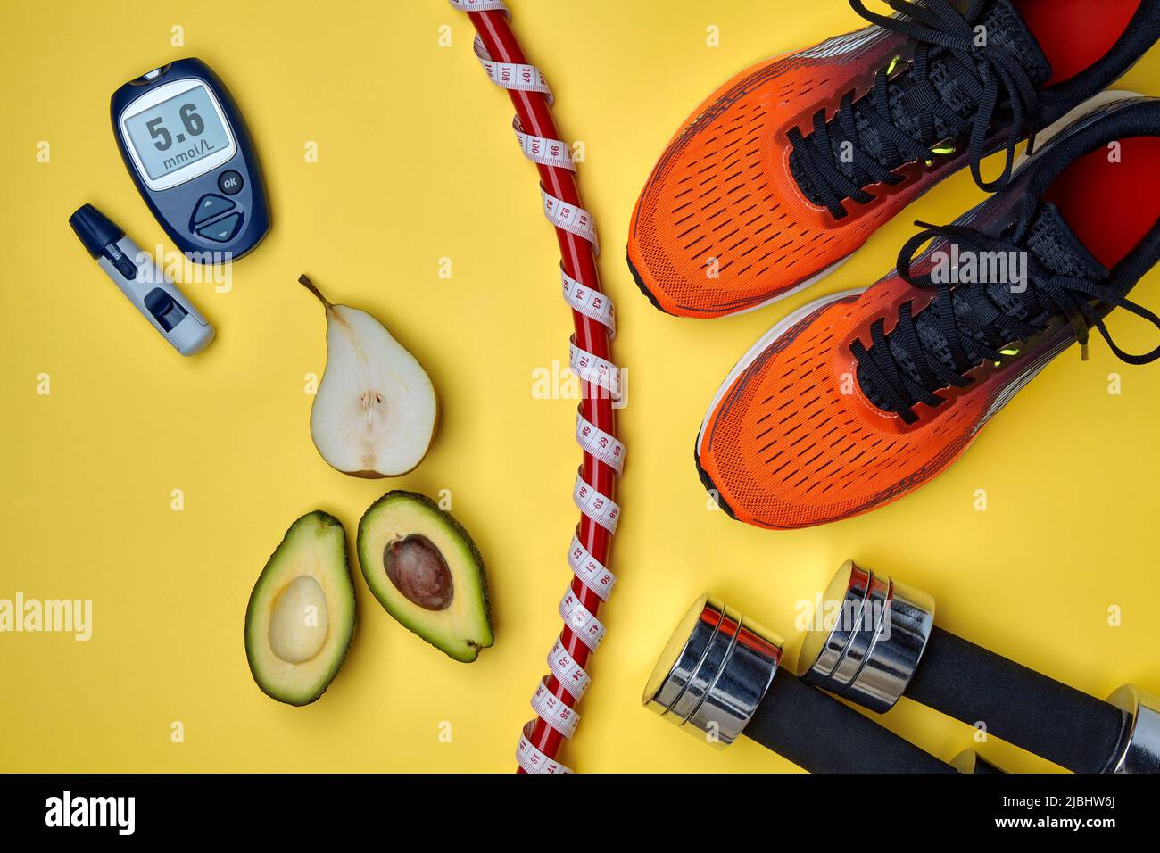 Orangefarbene Sport-Sneakers, Turnschuh, umwickelt mit einem Maßband mit einem Meter, Hanteln, Obst und einem Blutzuckermessgerät auf gelbem Hintergrund. E Stockfoto