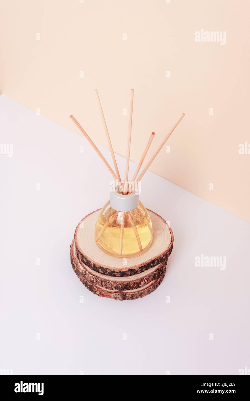 Glasflasche mit Duftdiffusor auf Holzständer auf weißem und neutralem beigen Hintergrund. Nahaufnahme. Stockfoto