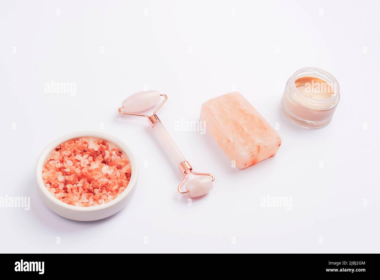 Himalaya-rosa Salz, Gesichtswalze, handgemachte Seife und Cremeglas auf weißem Hintergrund. Beauty-, Spa- und Self-Care-Konzept. Draufsicht. Stockfoto