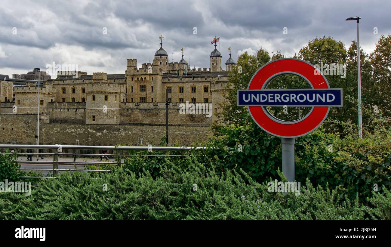 London, England - 17. Oktober 2019: Der mittelalterliche Palast der Tower of London steht einem modernen Schild der Londoner U-Bahn gegenüber. Stockfoto