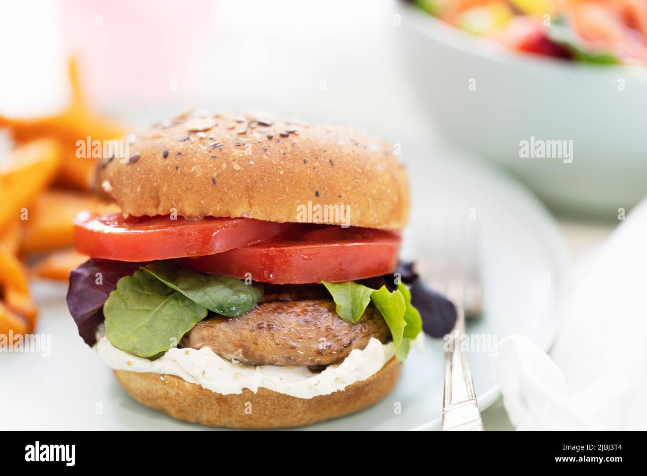 Gegrillter portobello-Pilz-Burger auf Vollkornbrötchen mit Süßkartoffelfritten. Stockfoto