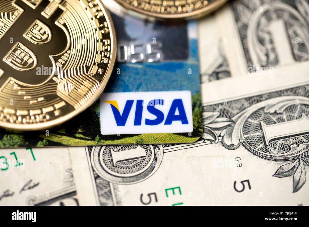 Bozen, Italien - April 10 2021: Bitcoin auf Visa-Kreditkarte und 1-Dollar-Banknoten. Digitales Geld mit Plastikgeld. Banknoten als Hintergrund. Soll Stockfoto
