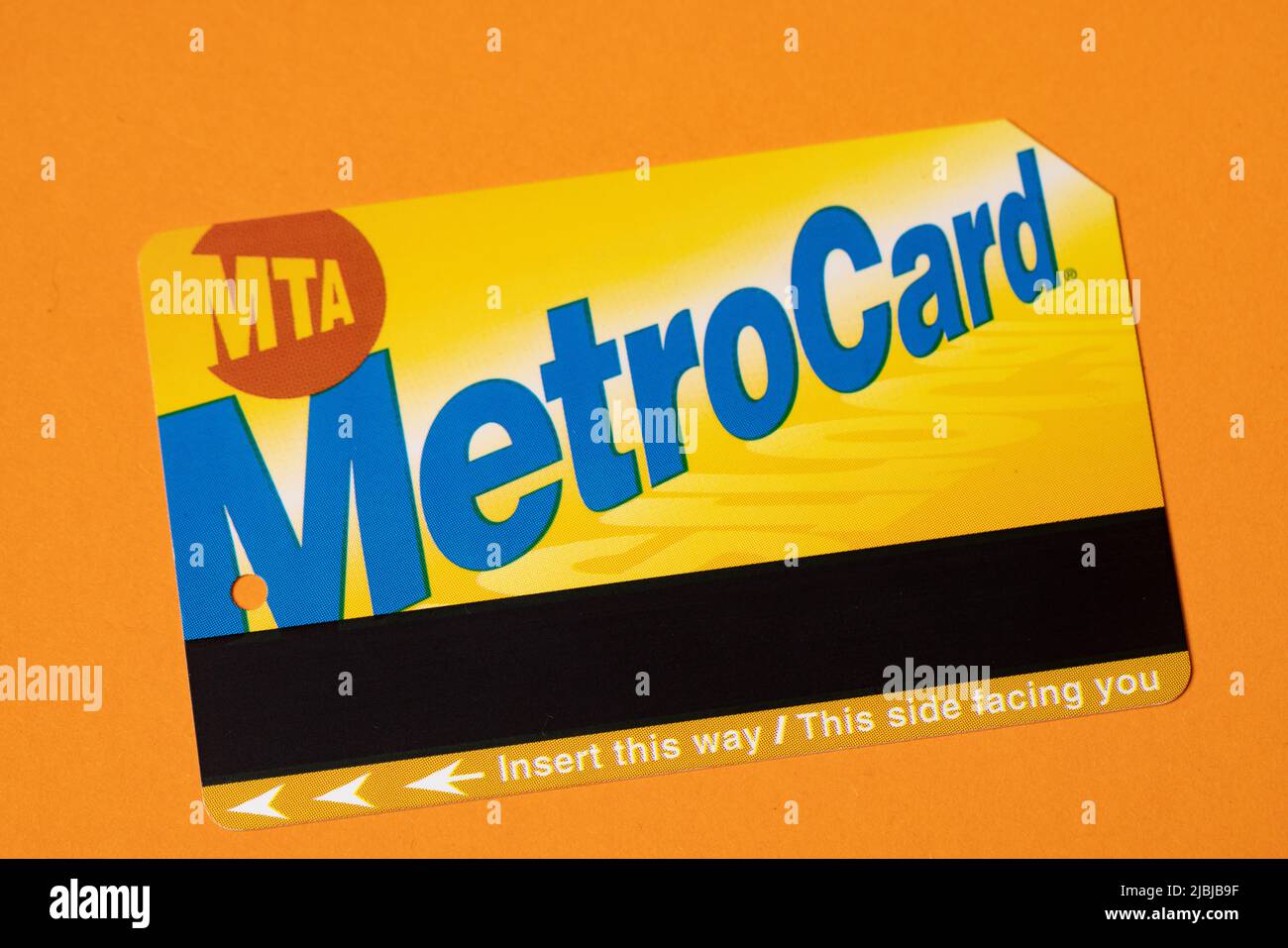 Manhattan, New York/USA - April 8. 2021: New York City Metrocard auf orangefarbenem Hintergrund. Ticket für den öffentlichen Nahverkehr in NYC Stockfoto